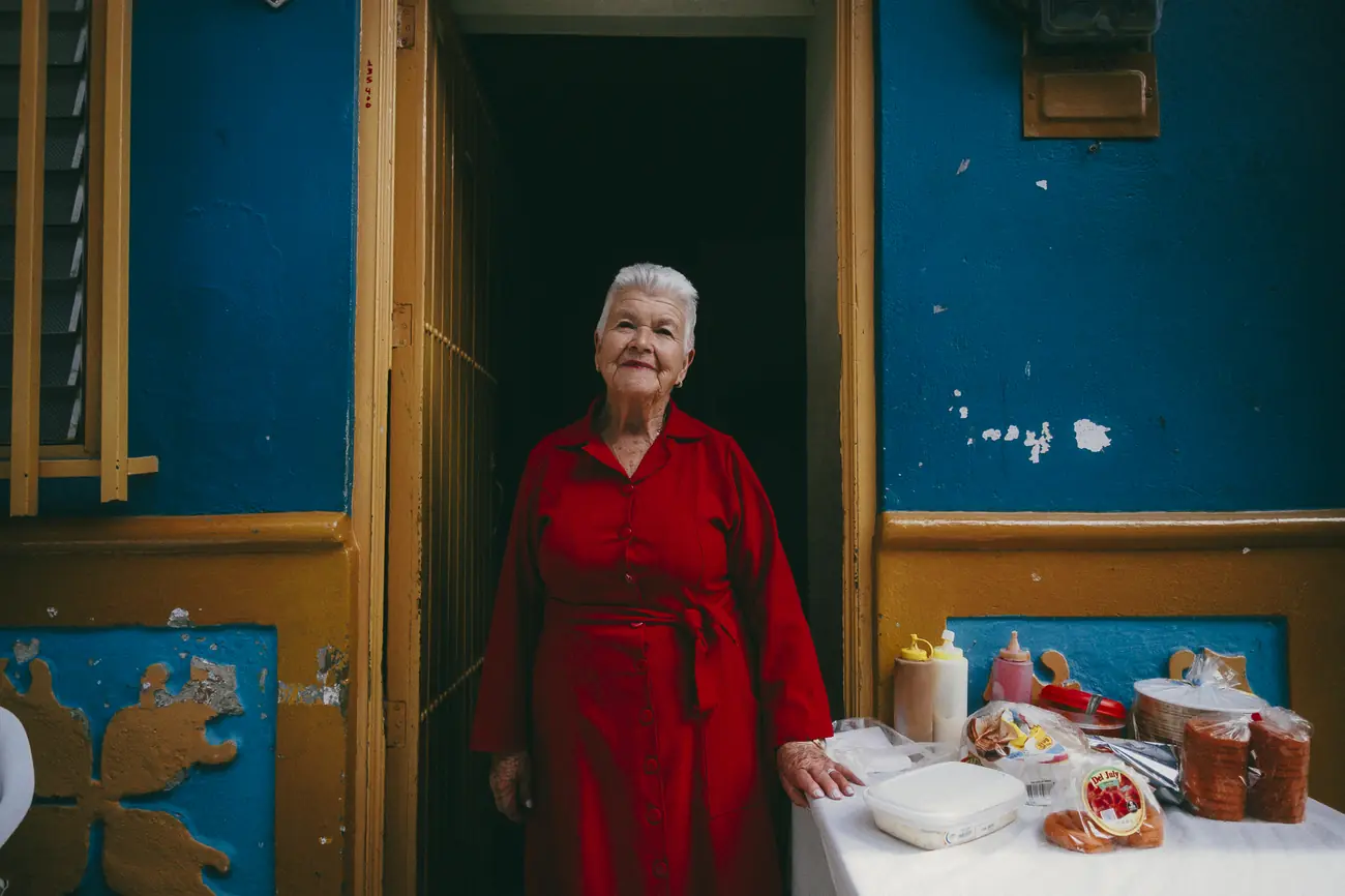 Retrato de senhora de vestido vermelho diante de parede azul e amarela