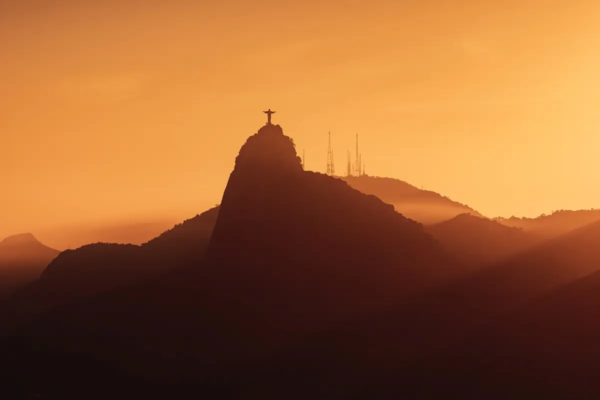 Silhueta do Corcovado ao amanhecer com céu alaranjado