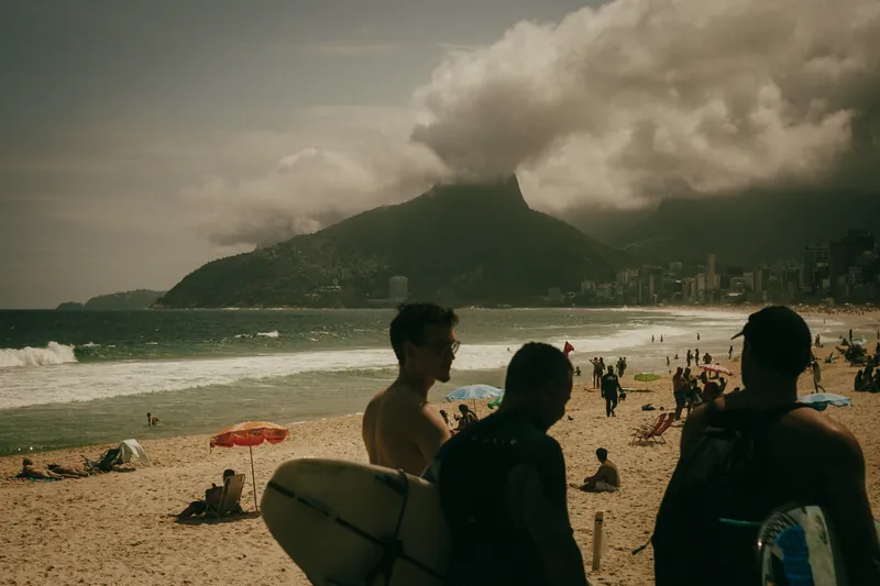 Capa do filme: surfistas na areia de Ipanema com uma nuvem cobrindo o Morro Dois Irmãos.