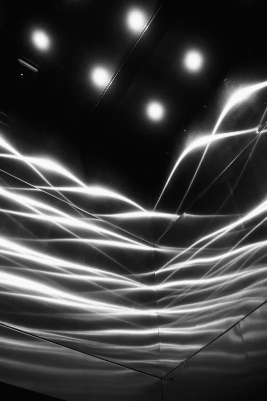 Ondas de luz refletidas em uma superfície metálica escura.