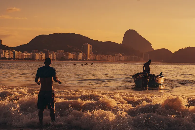 Pescadores empurrando o barco no amanhecer em Copacabana.