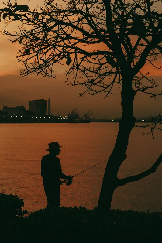 Pescador em silhueta no fim de tarde.
