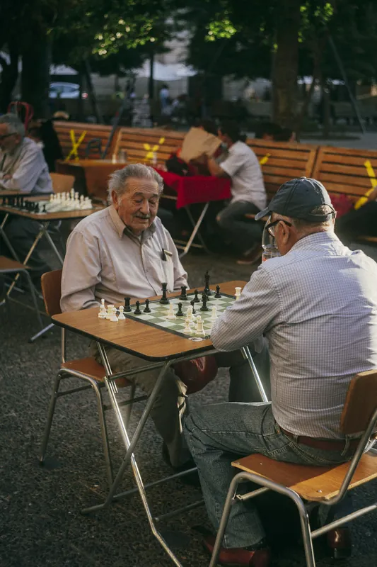 Cópia impressa de dois senhores jogando xadrez em uma praça.